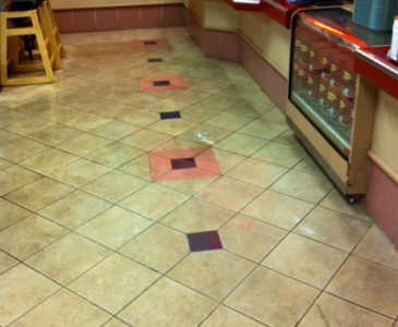 Before cleaning image of a commercial kitchen or serving area tile floor that is heavily soiled and discolored.