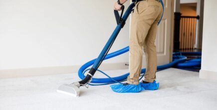 A person wearing booties steam cleans white carpet