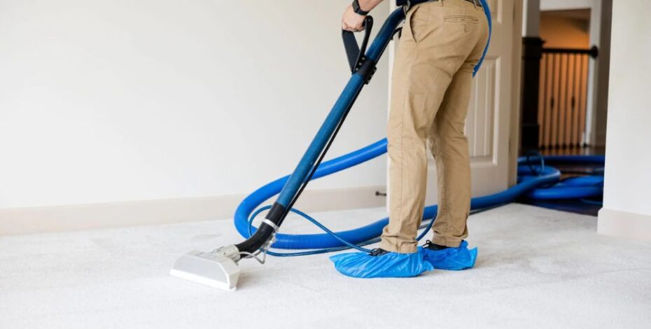 A person wearing booties steam cleans white carpet